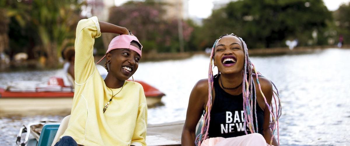 Two African women sitting in a boat and laughing.