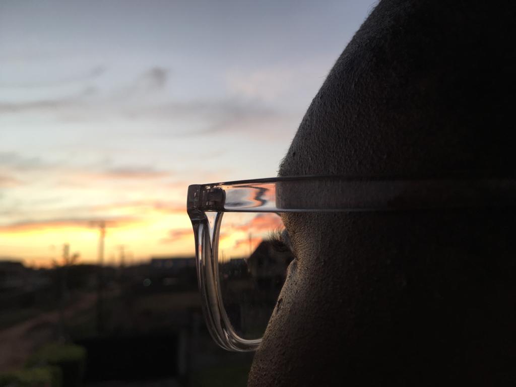Image contains a woman in glasses watching the sunrise