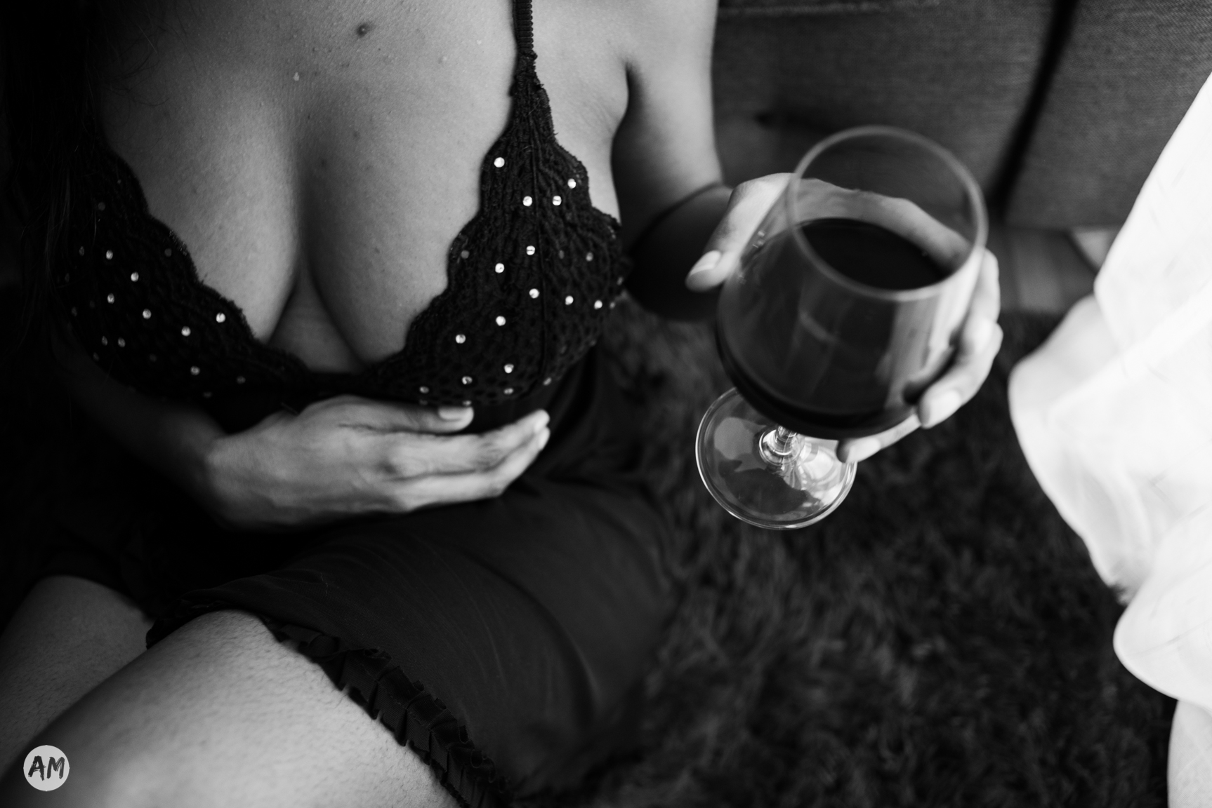 A black and white photo of a woman in lingerie holding a glass of wine