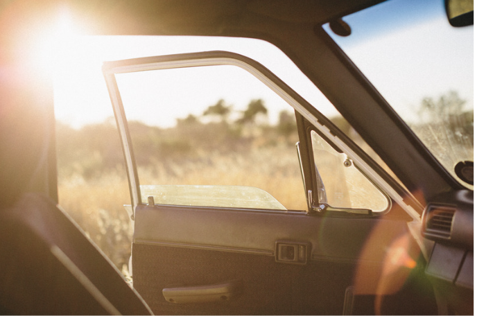 Passenger side door open of a parked car at sunset